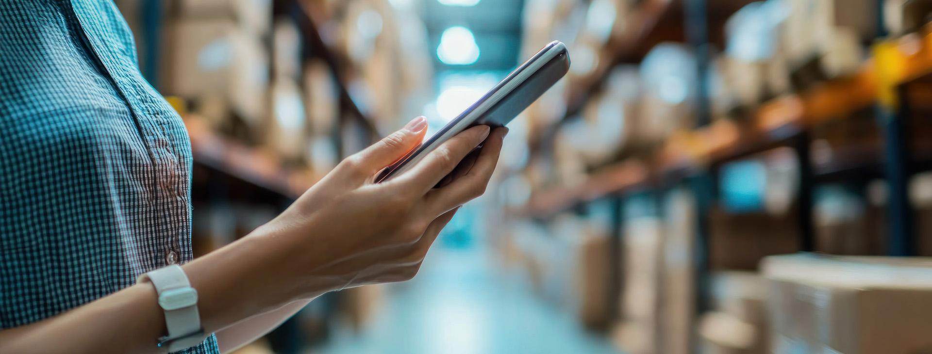 Personne consultant une tablette dans un entrepôt logistique
